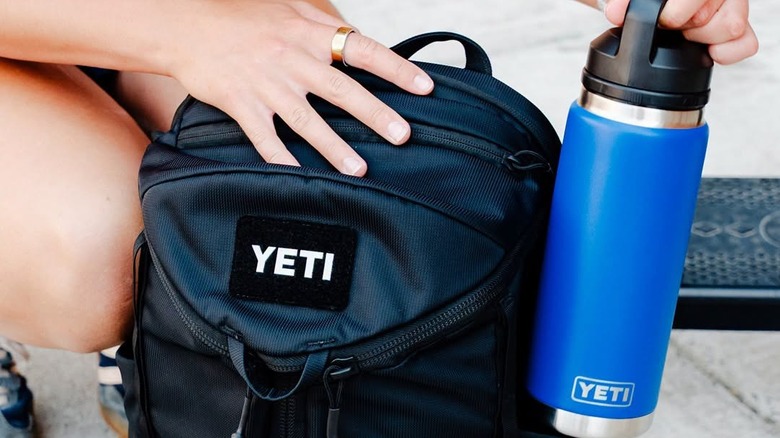 close up of a woman holding a Yeti water bottle near a backpack