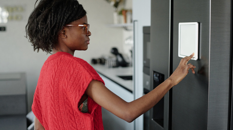 Woman using smart fridge display on door