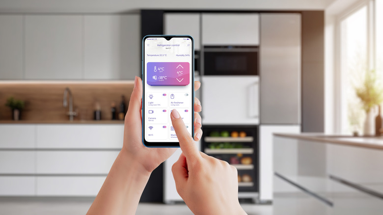 Person using app to control smart fridge temperature