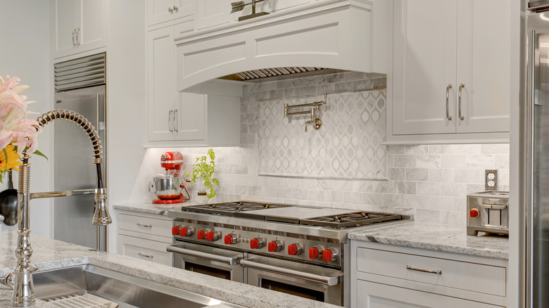 a pot filler over a stove with red accents throughout the kitchen