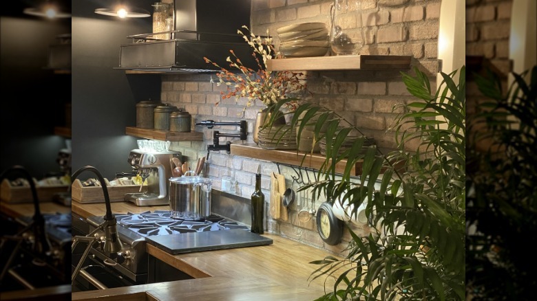 There is a black pot filler over a stove in a rustic and elegant kitchen
