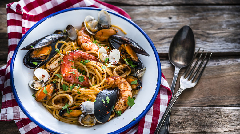 Plate of seafood pasta sits on a wooden table.