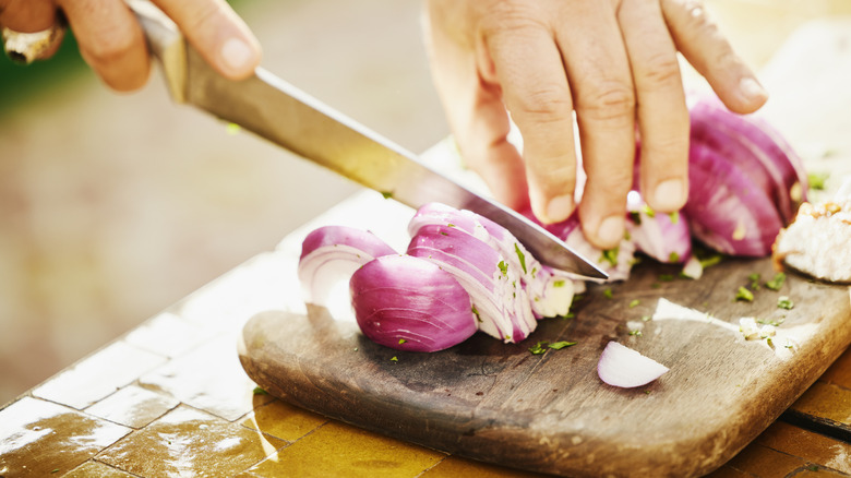 Red onions being sliced on a cutting board.