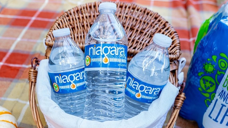 Three bottles of Niagara purified water in a woven basket, a package of the water to the side