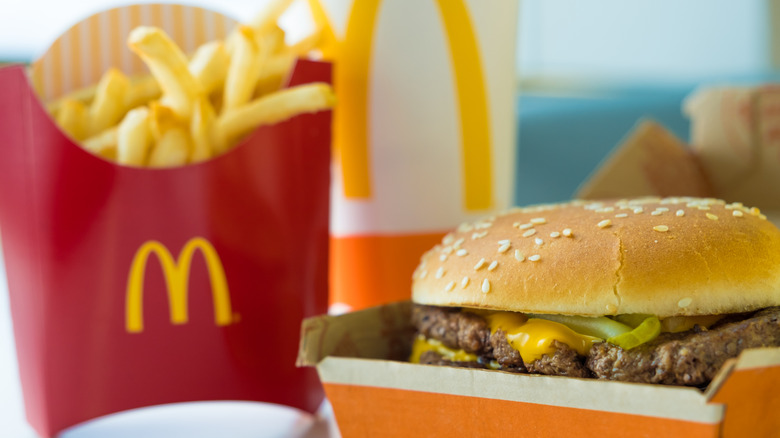 A double quarter pounder sits in its box, next to a box of McDonald's fries and a soda