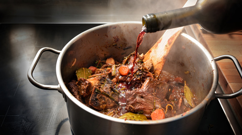 Wine poured into a braised beef dish.