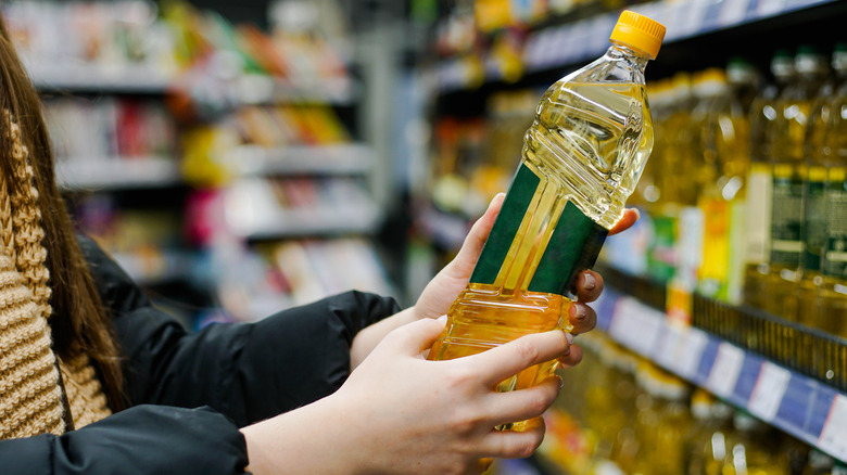 Woman holding canola oil in grocery store