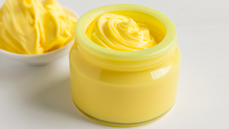 a jar of ghee with a bowl of it in the background