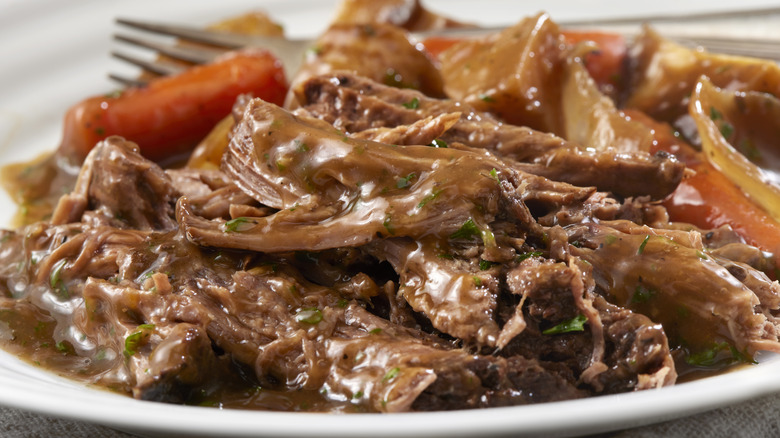A close up on a cooked Georgia pot roast sitting on a white plate