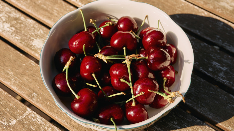 A bowl of cherries on a wooden table