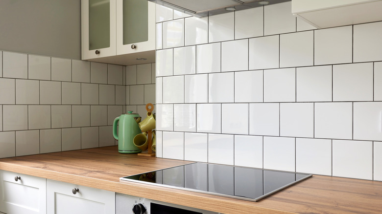 A kitchen backsplash featuring white subway tiles and a dark gray grout