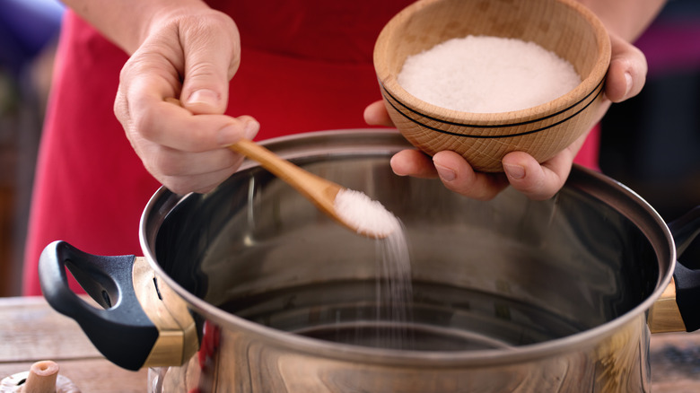 Person adding salt to water