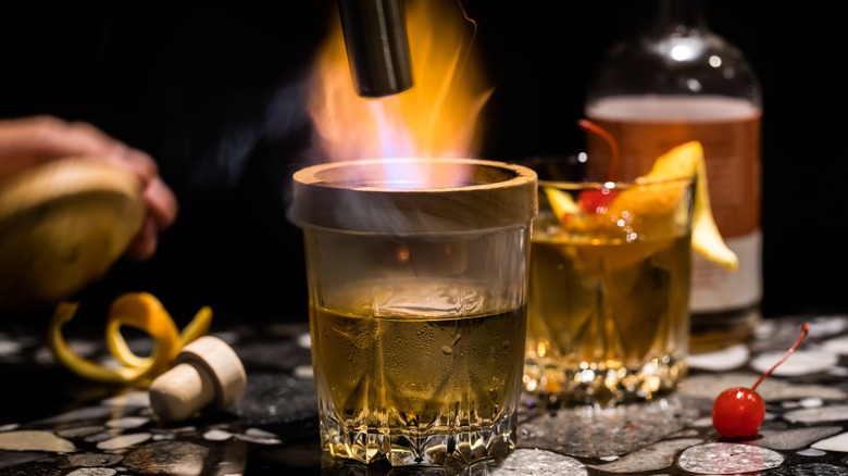 Making old fashioned whiskey cocktail with wood chip smoker