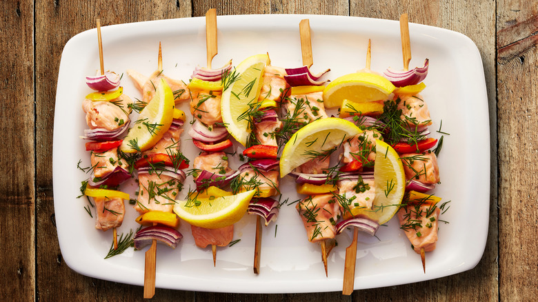 A plate of salmon and vegetable skewers.