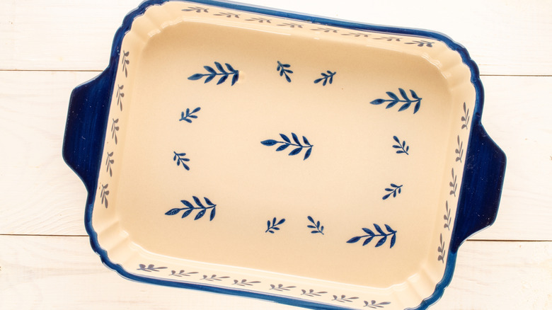 A ceramic dish that is blue on the outside and white on the inside with blue fern painted on it.