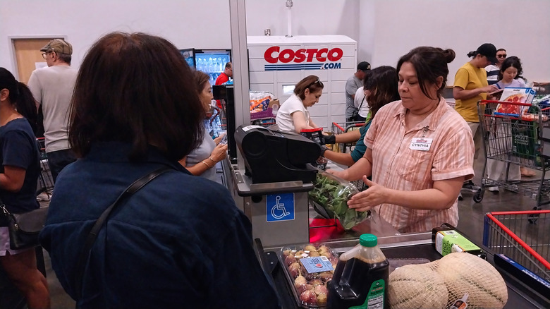 Customer at a Costco checkout with a worker ringing up the products