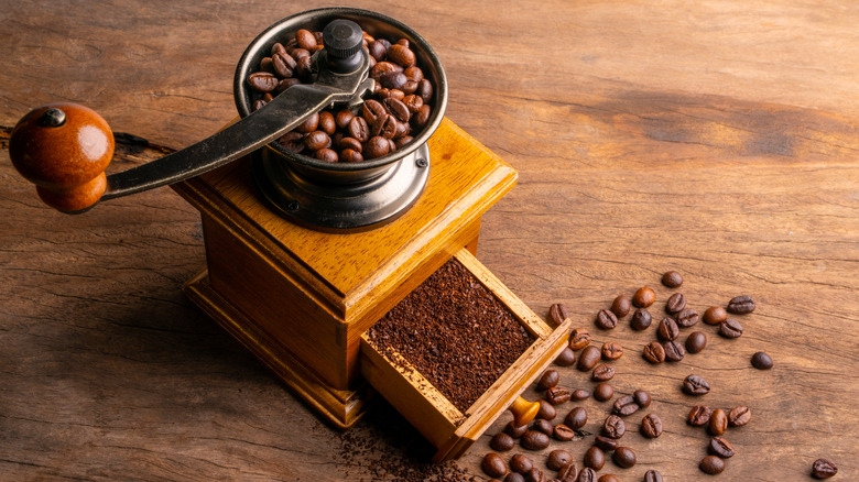 A coffee grinder surrounded by coffee beans