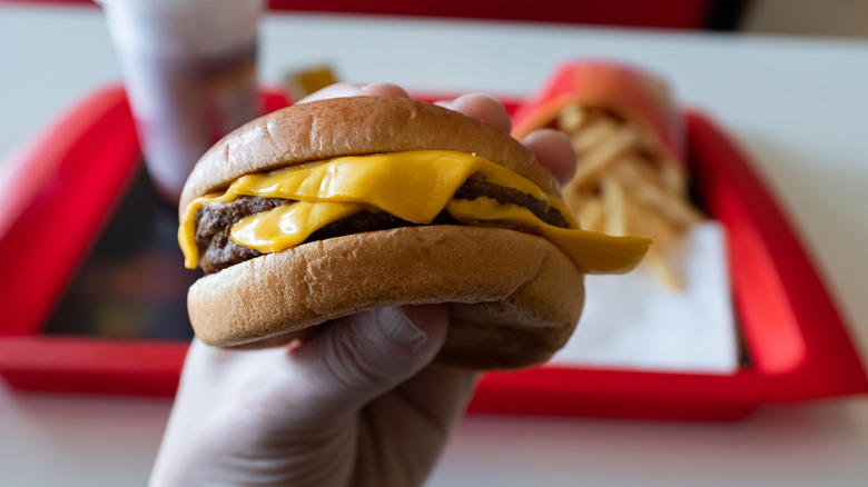 A young man is holding a piece of hamburger in his hands