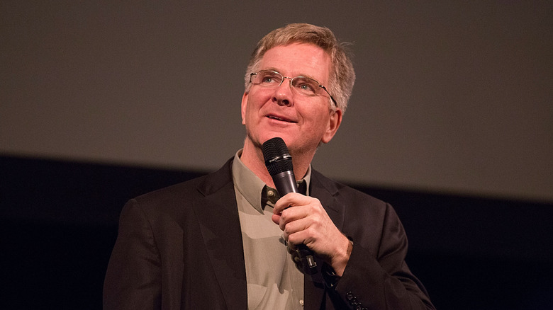 Rick Steves holding microphone on a stage