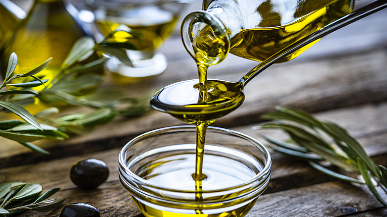 Olive oil pouring into spoon over bowl