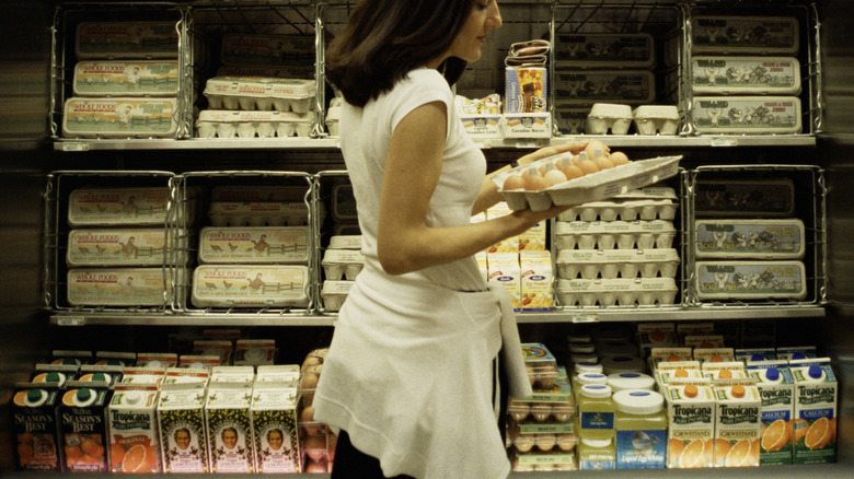 A woman holds an open carton of eggs in a grocery store