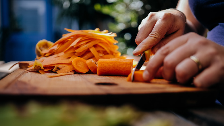 A person choping carots on a cutting board