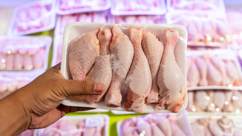 Hand holding chicken meat in grocery store