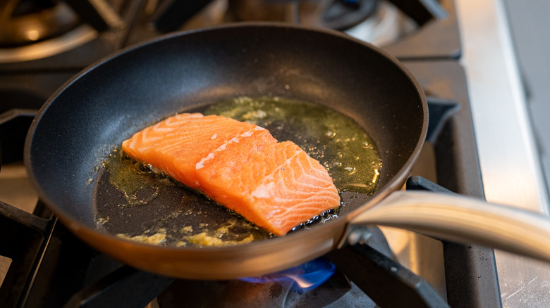 salmon steak being seared with the skin side down