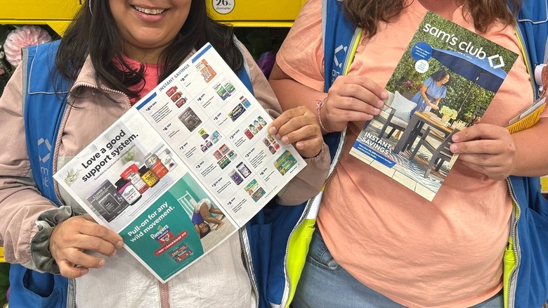 Two sales associates hold Sam's Club Instant Savings booklets in a store