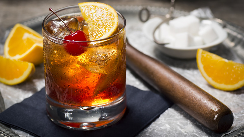 Old fashioned pictured alongside bartending tools.