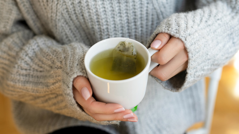 Hands holding a cup of green tea