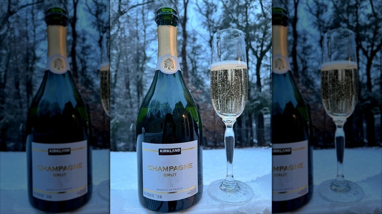 A bottle of the Kirkland Signature Brut Champagne next to a flute on Champagne.