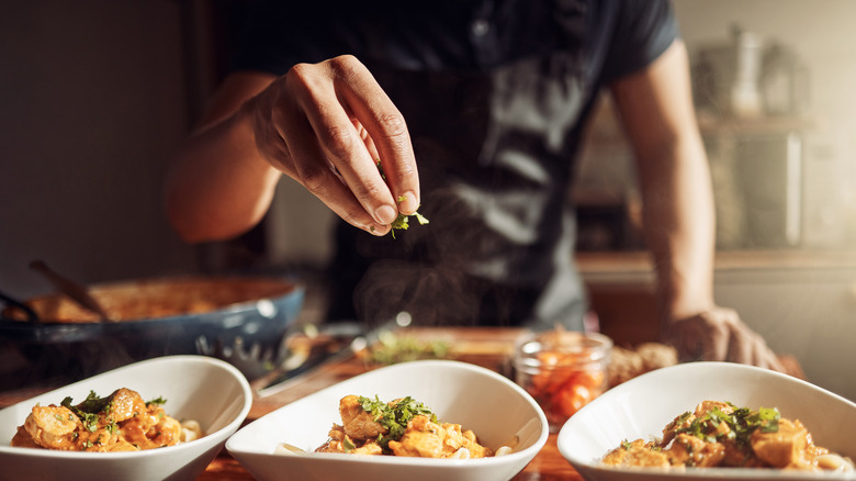 A chef adds garnishes to dishes.