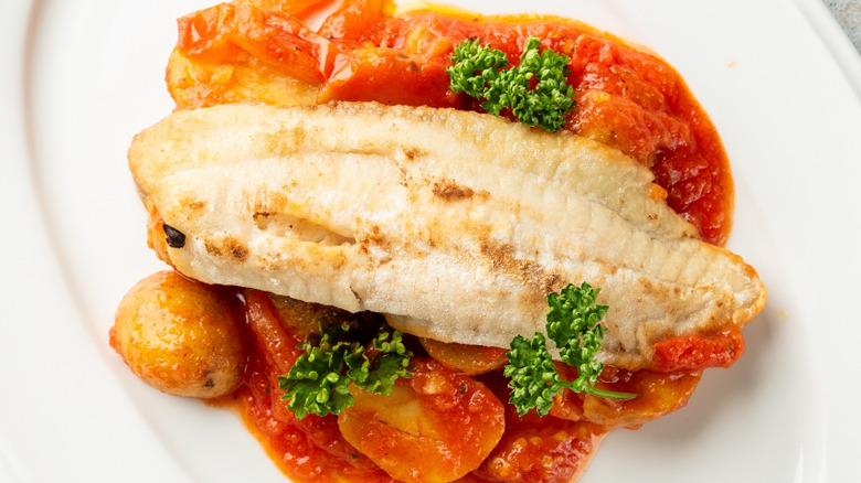 A fish dish garnished with curly parsley.