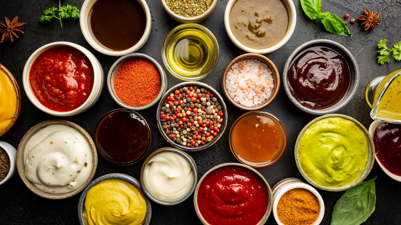 Various dips in small bowls surrounded by seasonings
