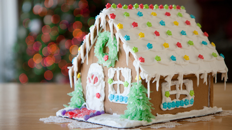 A gingerbread house decorated with white icing and colorful star sprinkles sits on a table.