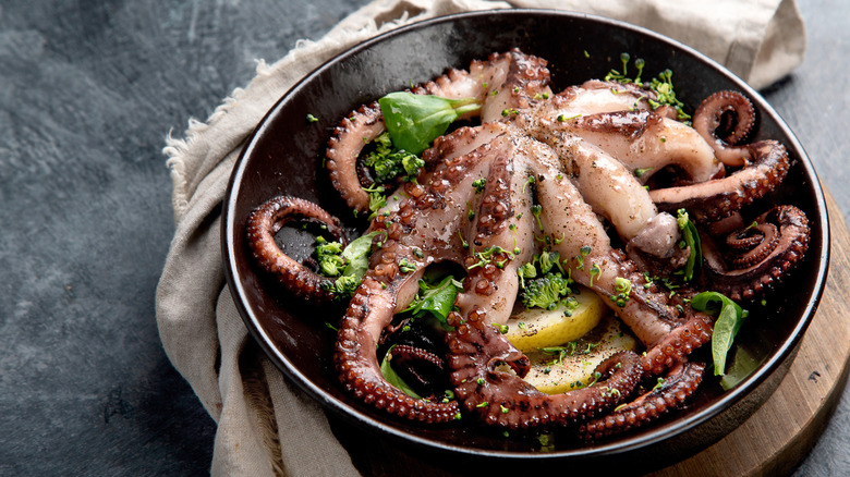 Cooked octopus with herbs in a pan.
