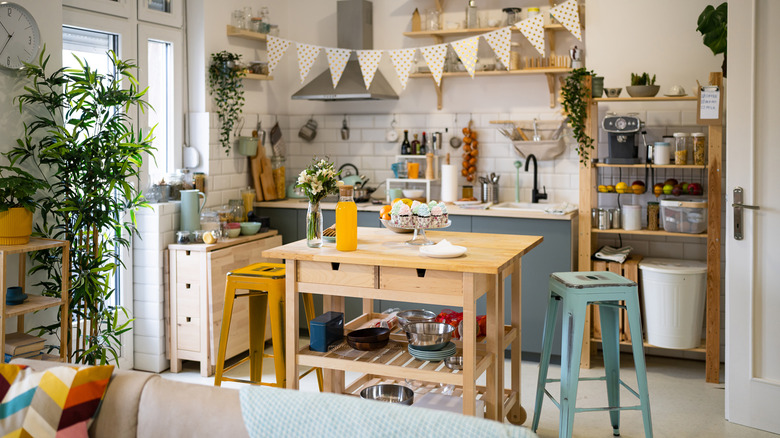 an unfitted kitchen with a wooden island on wheels