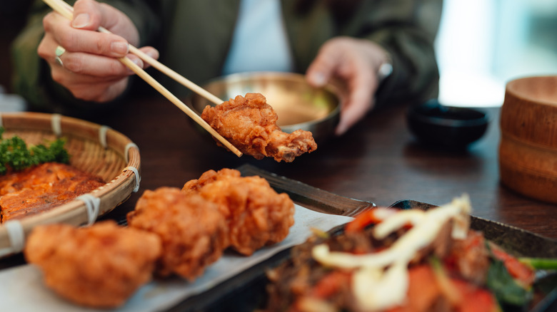 A diner picks up a fried chicken wing with chopsticks