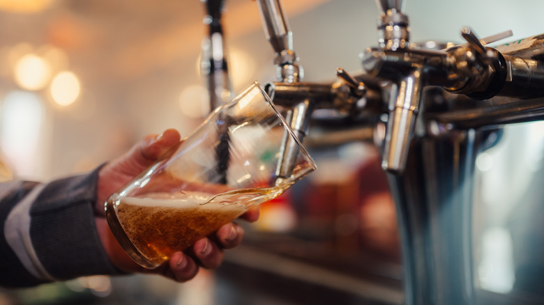 Bartender pulling a draft beer at a tap.