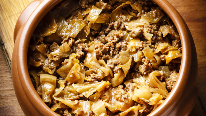 closeup of shallow clay pot with cabbage and beef stew inside