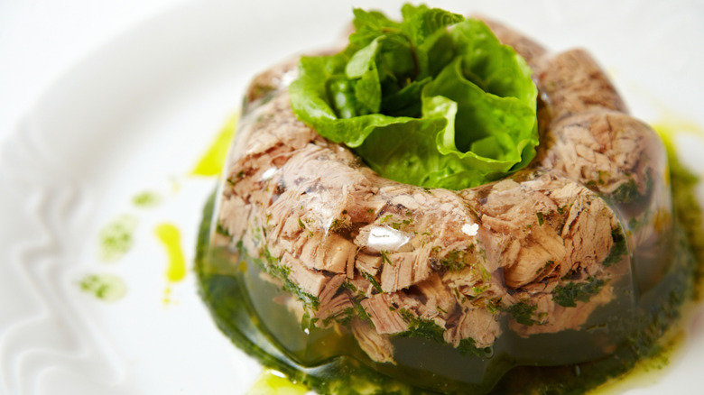 Pork jello salad is sitting on a plate with lettuce.
