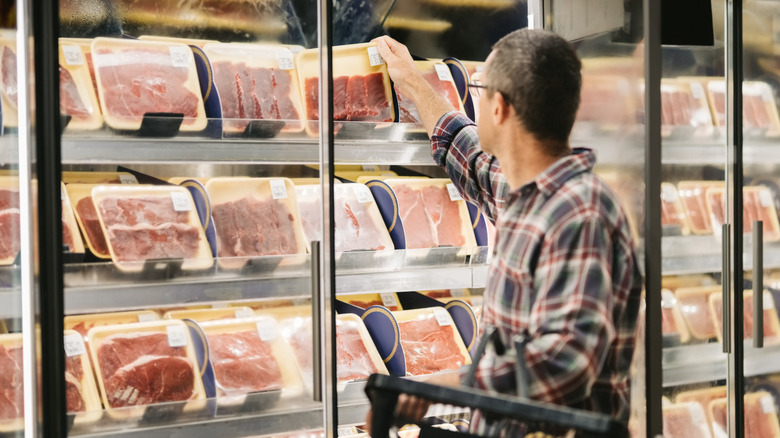 A shopper buying meat at a grocery store.