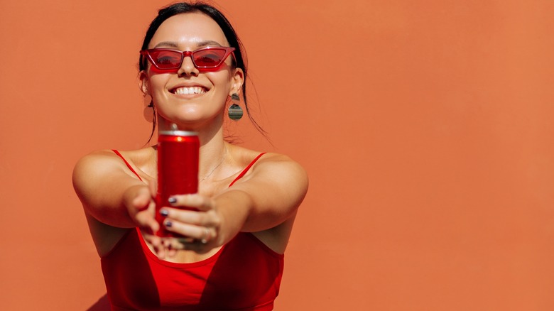 Smiling woman holding red can