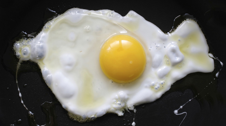frying egg against black background