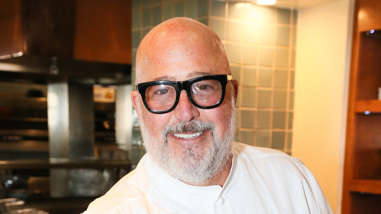 Chef Andrew Zimmern with large black glasses smiling at an event