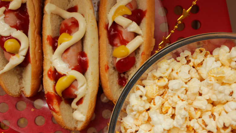 Hot dogs in buns next to a bowl of popcorn