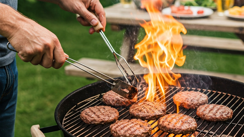 Burger patties being cooked on a charcoal grill