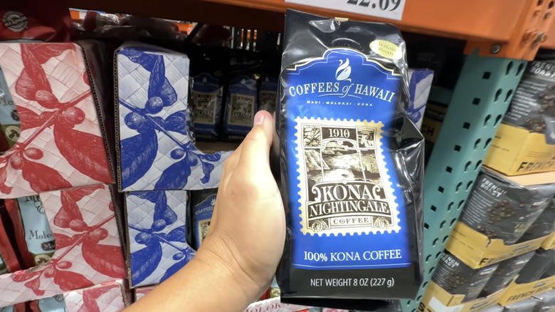 A hand holding 100% Kona coffee in a Costco.
