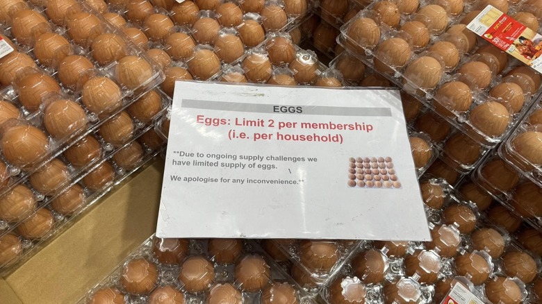 A sign limiting the number of eggs customers can purchase at a Costco sits on cartons